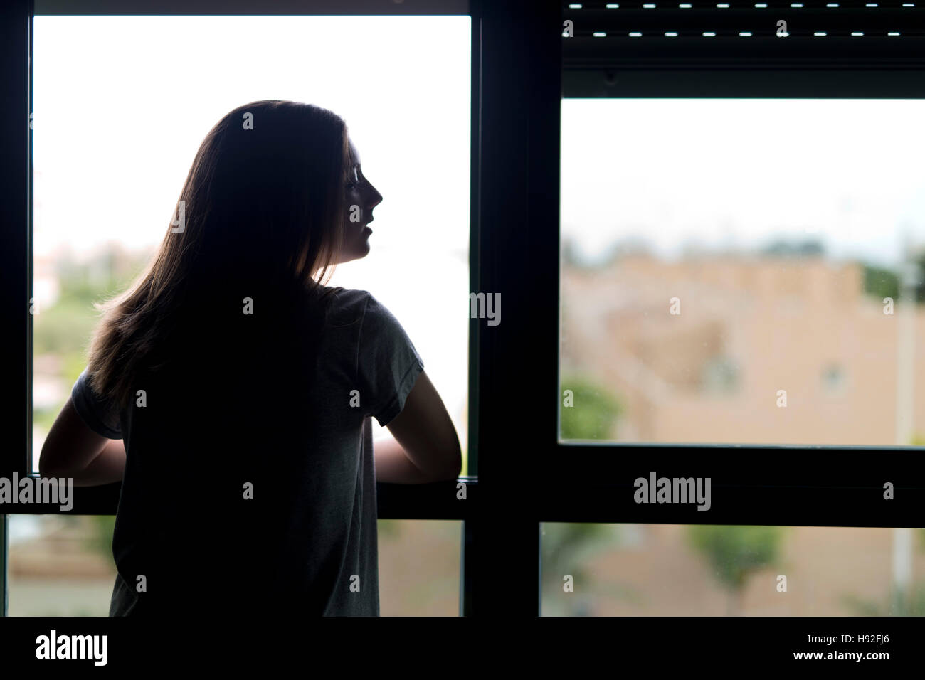 Teenager in der Nähe eines Fensters. Hintergrundbeleuchtung mit textfreiraum Beleuchtung. Stockfoto