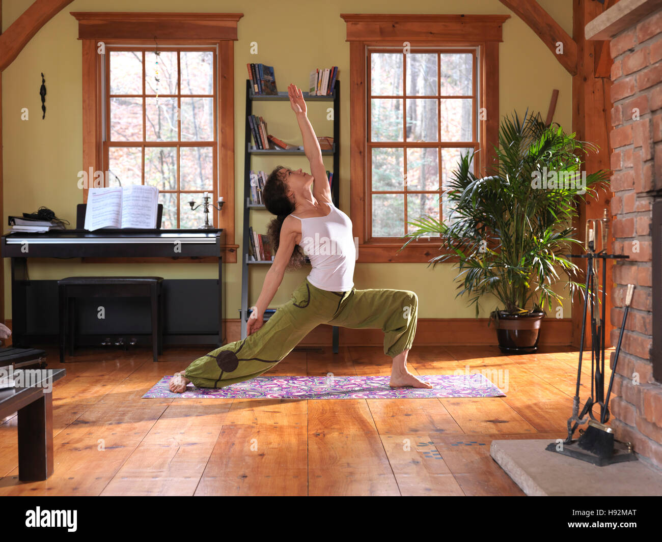 Junge Frau praktizieren Yoga drinnen im Wohnzimmer an einem sonnigen Tag Stockfoto