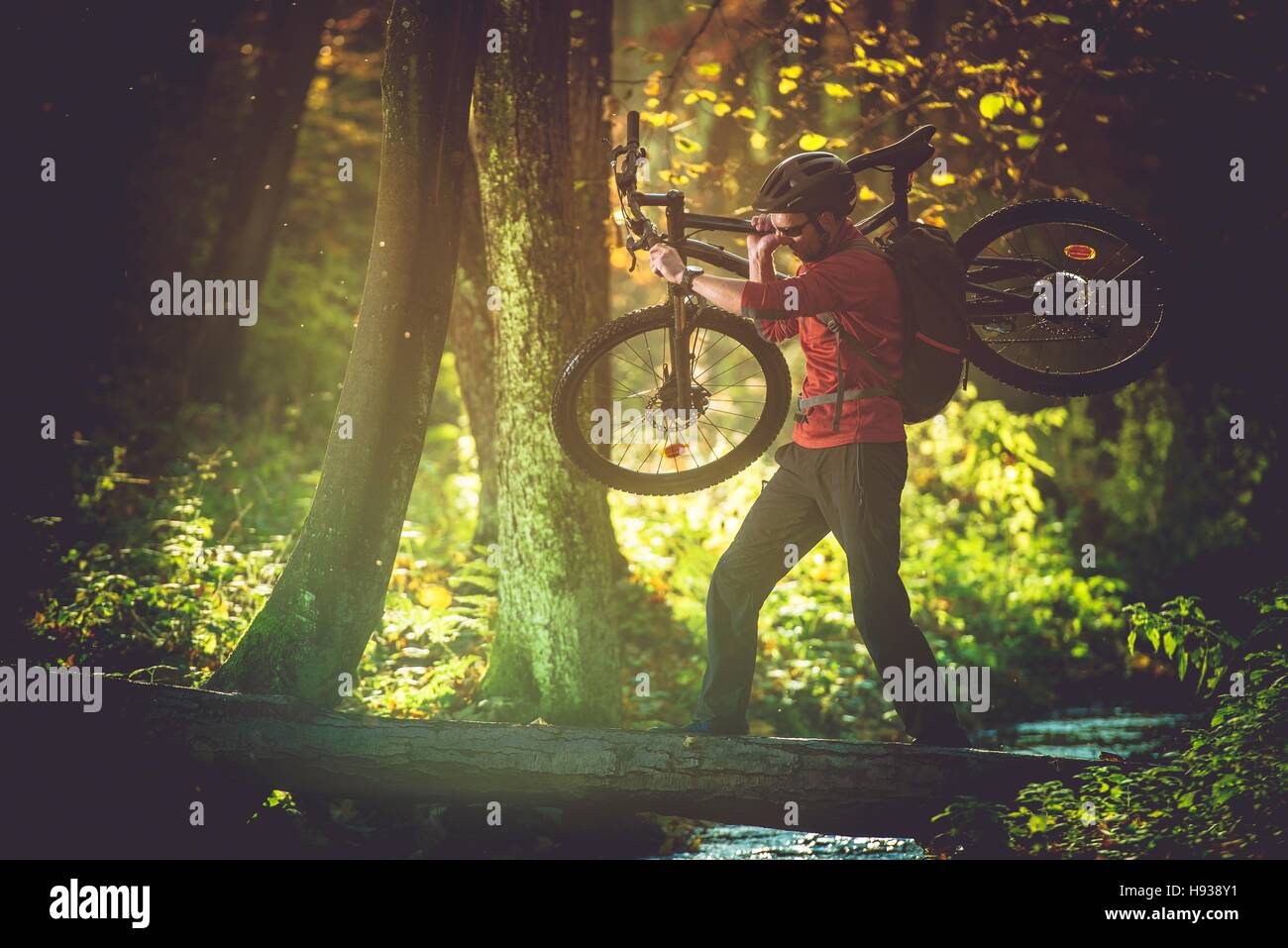 Wildnis-Radtour. Männer mit Mountain Bike Crossing kleine Gebirgsfluss mit seinem Motorrad in Händen. Stockfoto