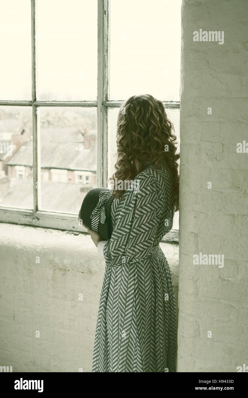 Frau in Vintage-Kleid aus dem Fenster Stockfoto