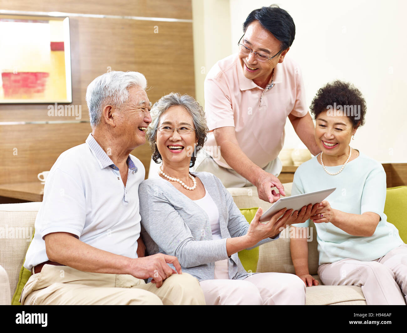 zwei aktive senior asiatische Paare betrachten Tablet-Computer, glücklich und lachend Stockfoto