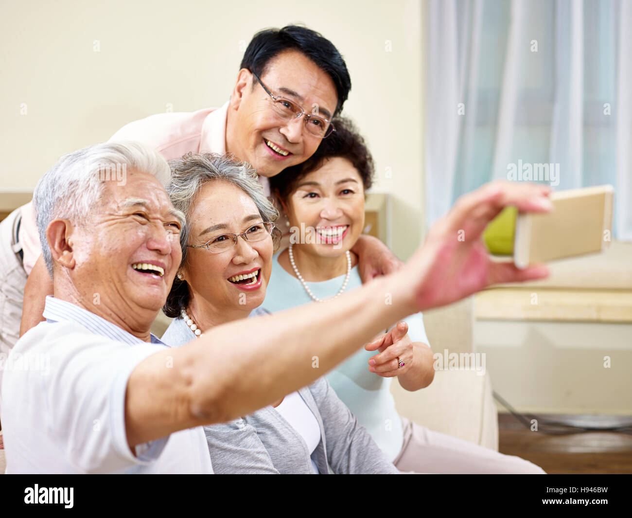 zwei aktive senior asiatische Paare nehmen ein Selbstporträt mit Handy, glücklich und lächelnd Stockfoto