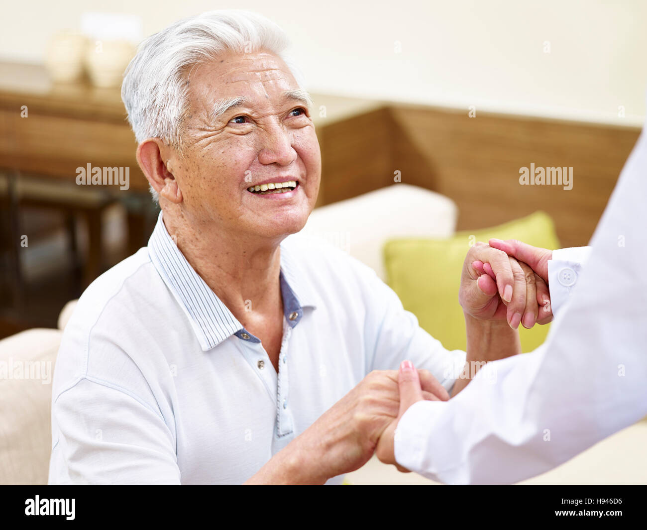 glücklich und lächelnd senior asiatischen Mann in seine 80er Jahre immer unterstützt durch medizinische Arbeiter Stockfoto