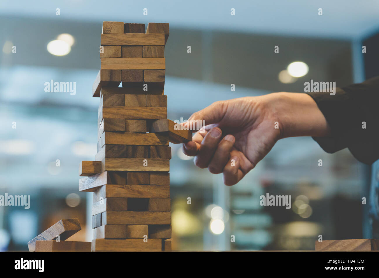 Planung, Risiko und Strategie in der Wirtschaft, Geschäftsmann Glücksspiel Platzierung Holzblock auf einem Turm - Unschärfe für Hintergrund Stockfoto