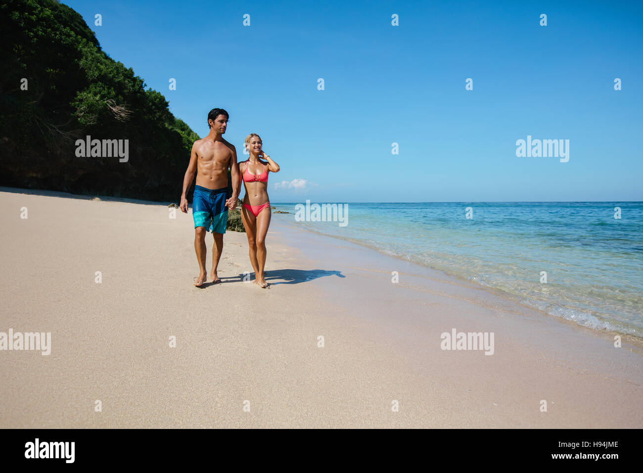 Voller Länge Aufnahme des jungen Flitterwochen am Strand. Junger Mann und Frau ein Spaziergang am Ufer Meeres. Stockfoto