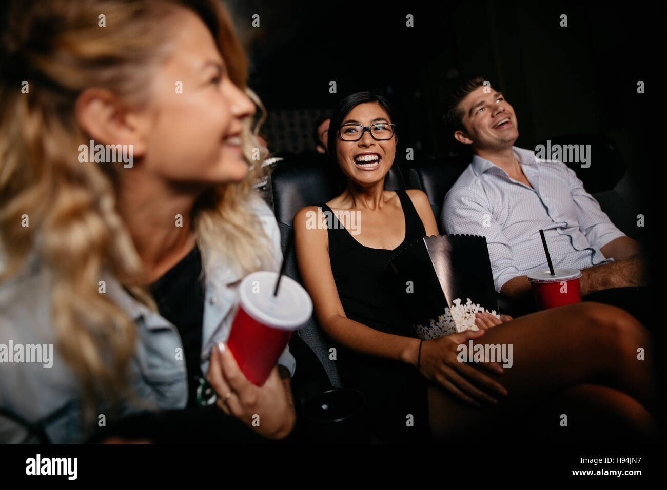 Junge Frau mit Freunden Film im Kino. Gruppe von Personen bei Theaterbestuhlung. Stockfoto
