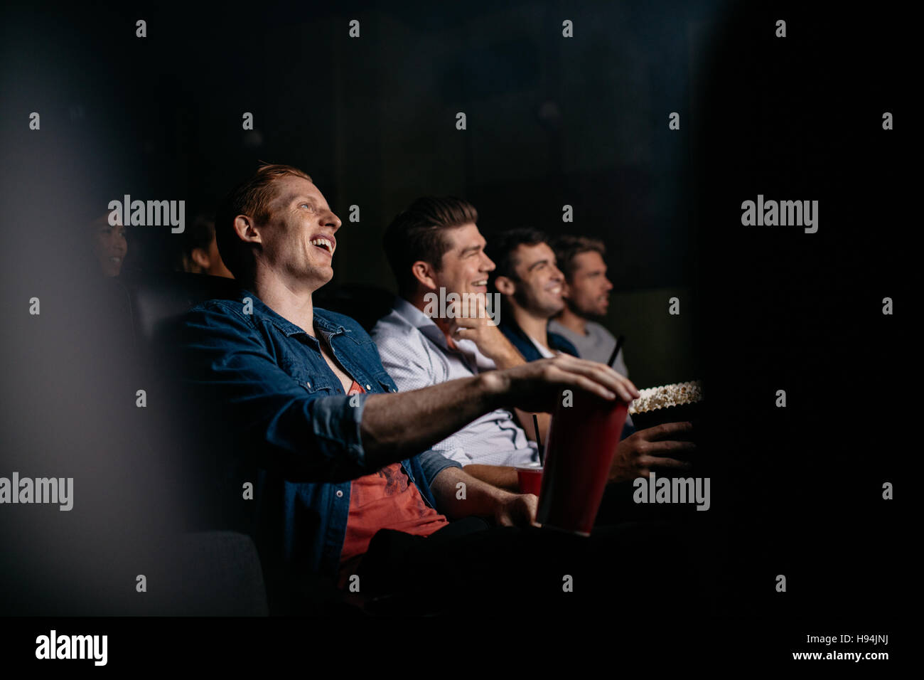 Gruppe von Freunden sitzen im multiplex-Kino. Junge Menschen Film im Kinosaal und lächelnd. Stockfoto