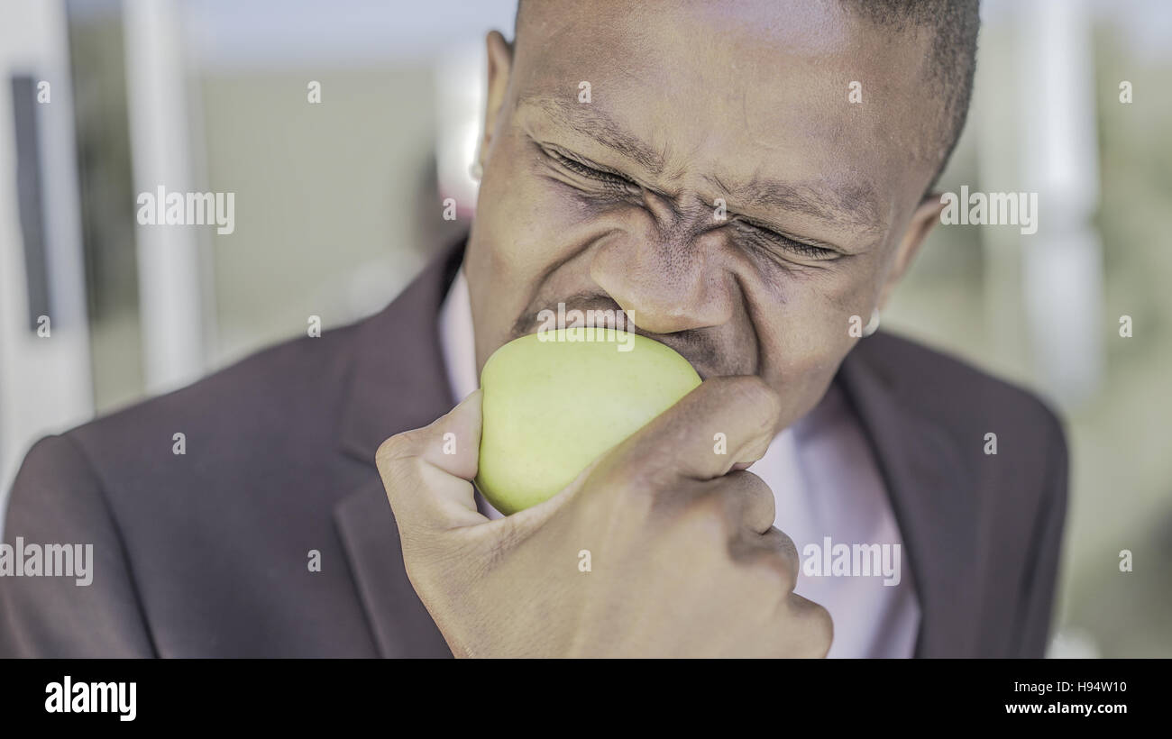 Afrikanischer Mann isst einen Apfel Stockfoto