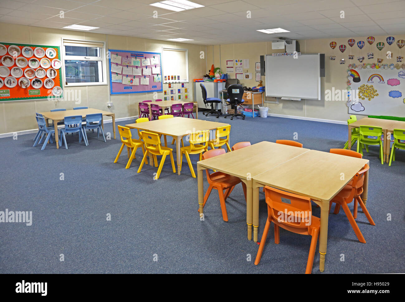 Innenansicht einer modernen Jahr 1 Schulklasse mit Tischen, Stühlen und Kunstwerke an Wänden in leuchtenden Farben Stockfoto