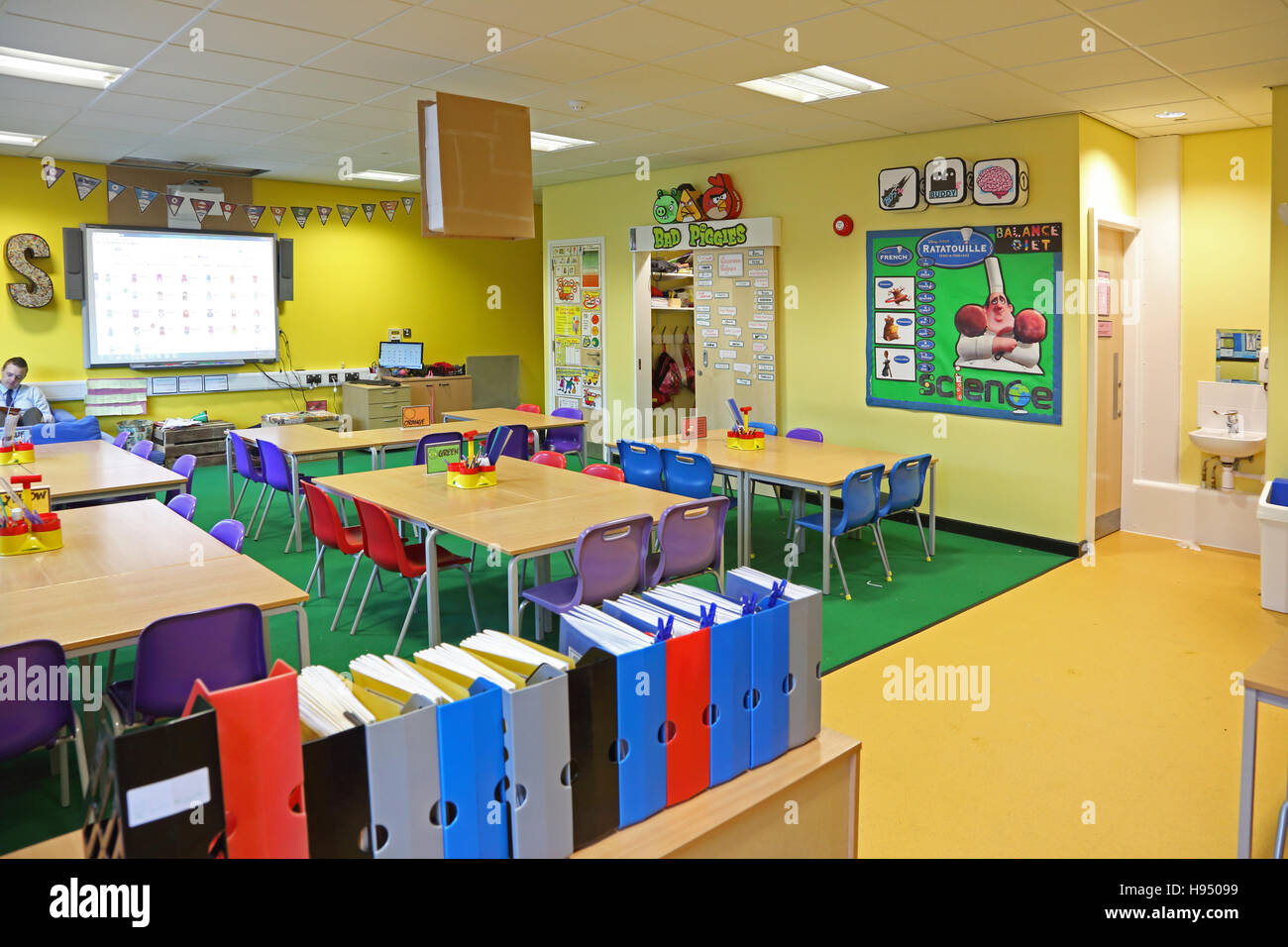 Innenansicht einer modernen Jahr 1 Schulklasse zeigt, Tische, Stühle, Computer-Bildschirm und Kunstwerke an Wänden in leuchtenden Farben Stockfoto