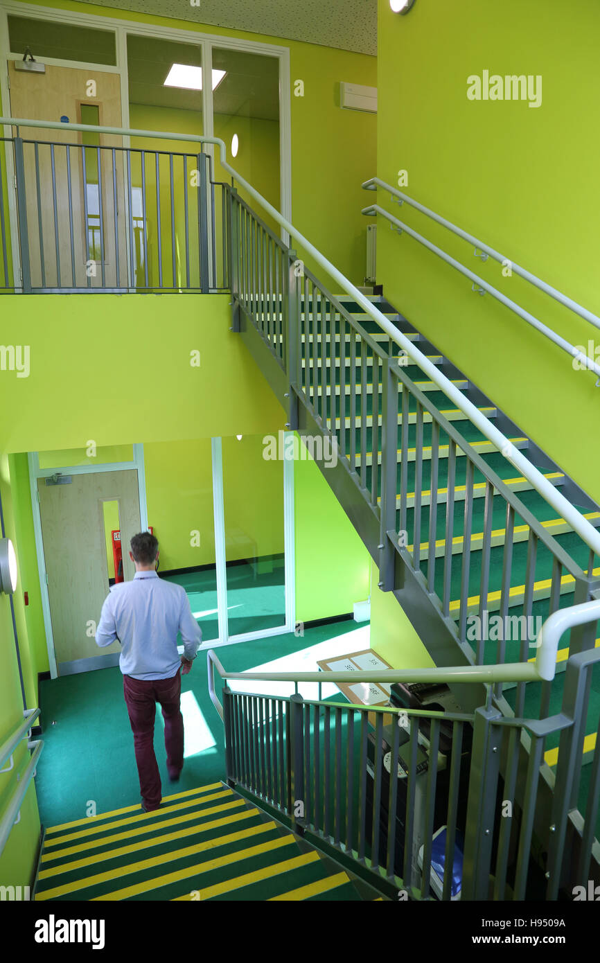 Ein Lehrer steigt eine Stahltreppe in eine neue Schule Klassenzimmer Block mit Modulbauweise konstruiert. Grüne Wände. Stockfoto
