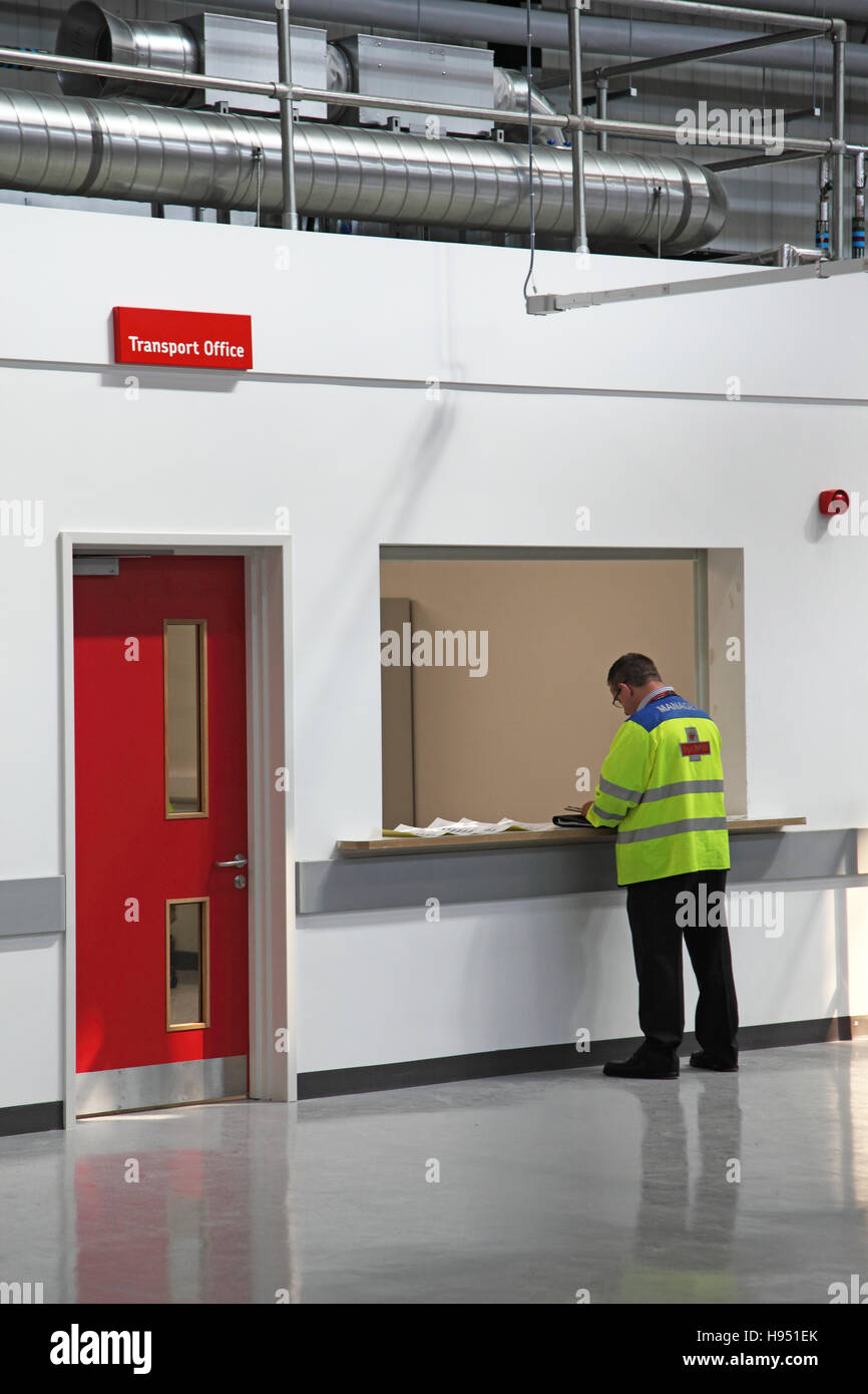 Ein Postbote wartet an der Rezeption Transport Office in ein neues Postamt Sortierung Büro im südlichen England, UK Stockfoto