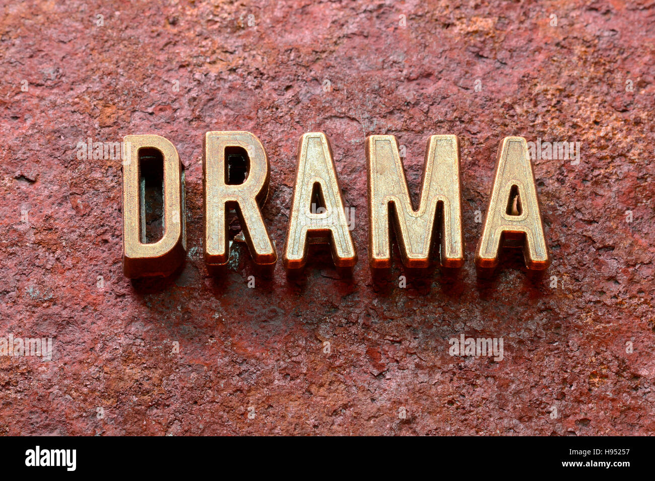 Drama-Wort, das aus metallischen Lettern auf rotem rostige Oberfläche Stockfoto