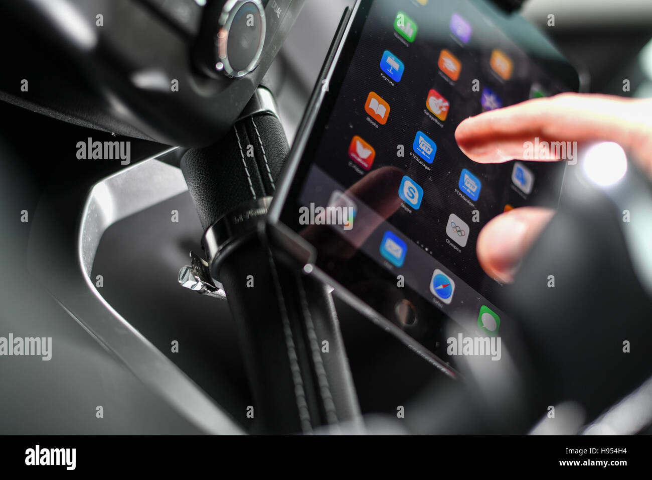 Eine Autofahrer betreibt seine iPad, die in eine integrierte Halterung während Autofahren entlang einer Landstraße in Friedrichshafen, Deutschland, 18. November 2016. Das Gesetz ist, dass jemand mit einem Mobiltelefon gefangen während der Fahrt ist erforderlich, um eine Geldstrafe zu zahlen. Aber bisher das Schreiben einer SMS oder die Verwendung eines Tablet-PCs nicht ausdrücklich in der Straßenverkehrsordnung und der Bundesminister für Verkehr verboten ist jetzt will das ändern. Foto: FELIX KAESTLE/DPA Stockfoto