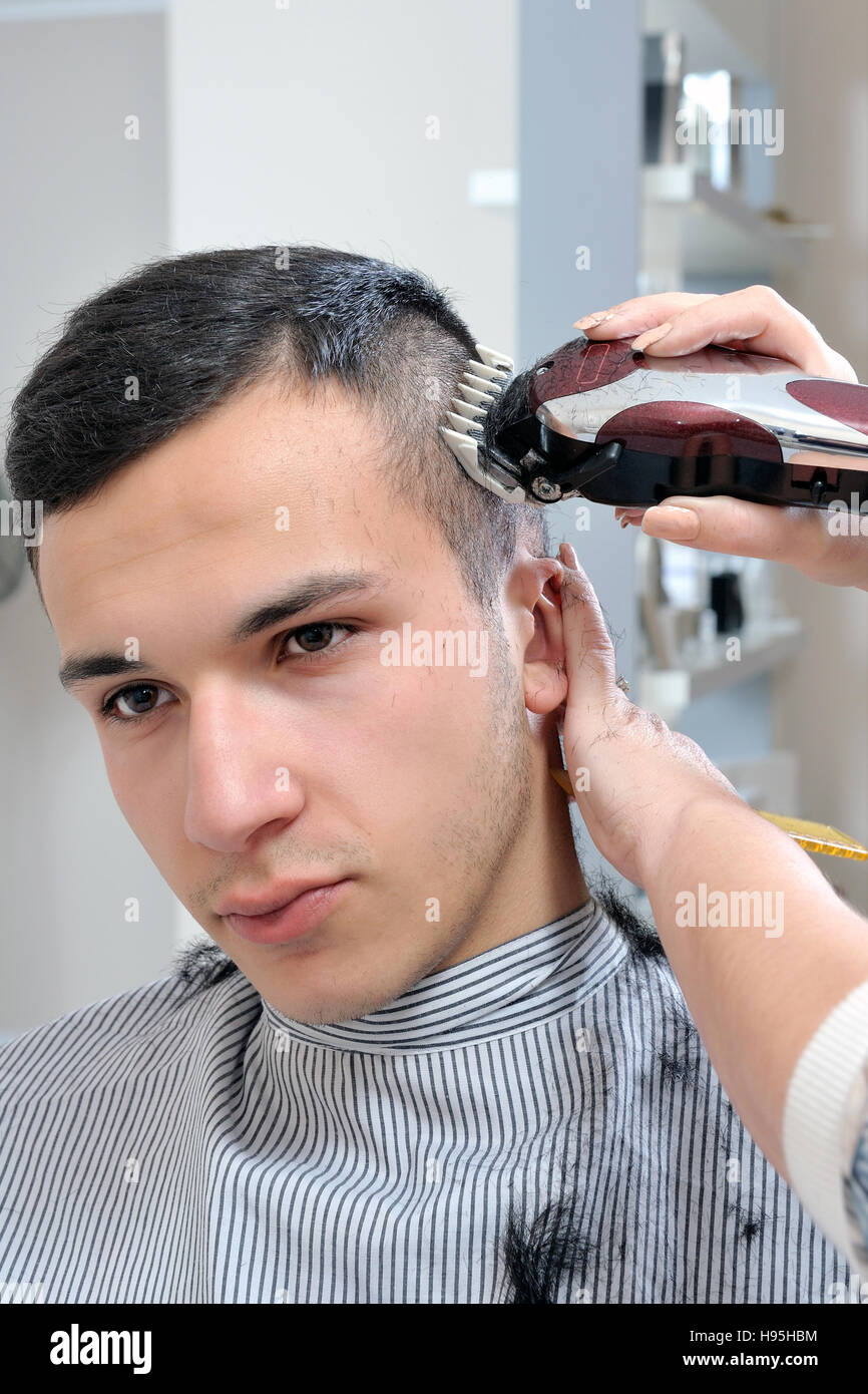 Friseur, die die Frisur eines jungen Mannes mit elektrischen Haarschneider  ausführt Stockfotografie - Alamy