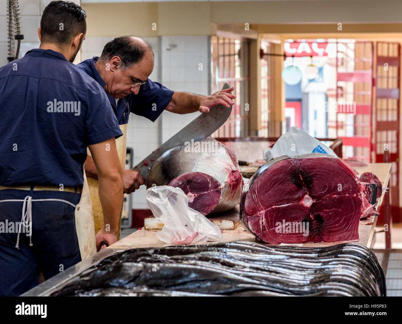 Arbeiter in der Fischmarkt zerschneiden ein riesiger Thunfisch mit einem riesigen Messer Stockfoto