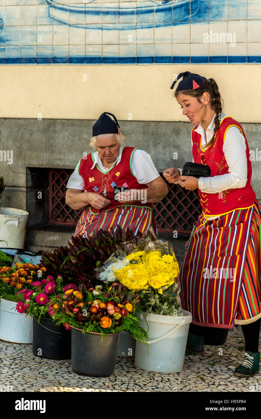 Blumenverkäufer im traditionellen Kostüm auf Madeira Funchal Markt mit bunten tropischen Blumen Stockfoto