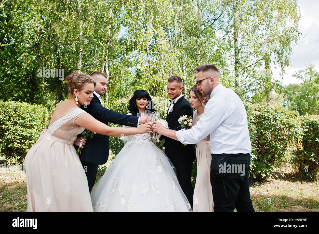 Stilvolle Hochzeitspaar, Brautführer und Brautjungfern outdoor Champagner trinken. Stockfoto