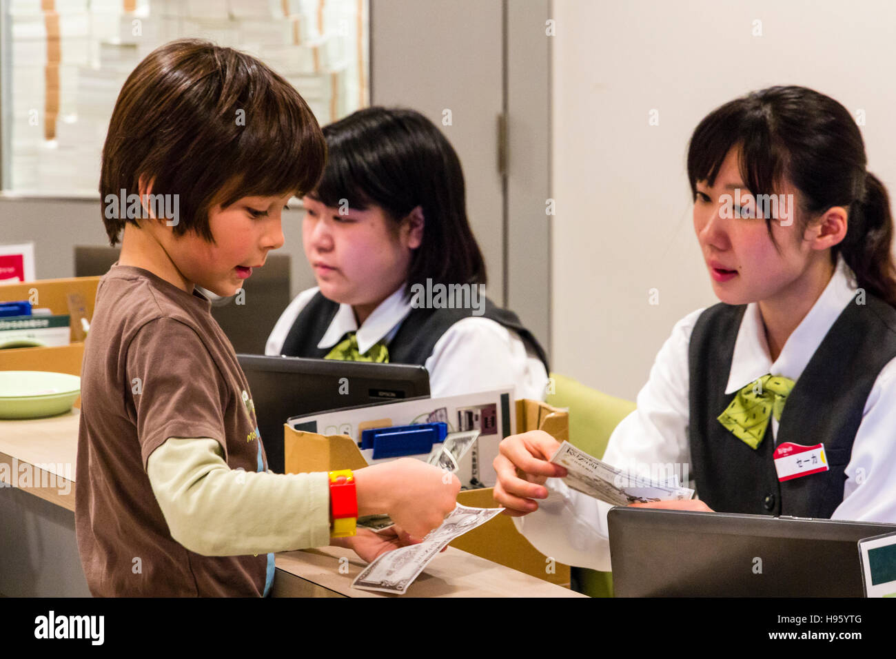 Japan, Nishinomiya, KidZania. Kinder spielen. Bank, Interieur, Western Kind, 9-10 Jährige, Geld entziehen nach japanischen Frau Kassierer. Stockfoto