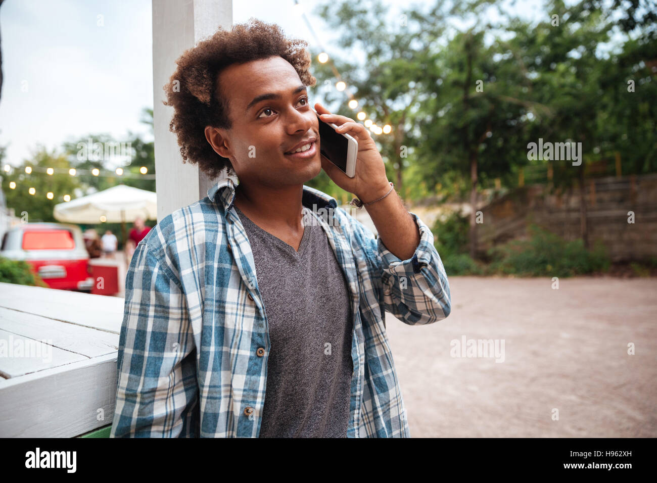 Glückliche afrikanischen jungen Mann stehen und reden auf Handy im freien Stockfoto