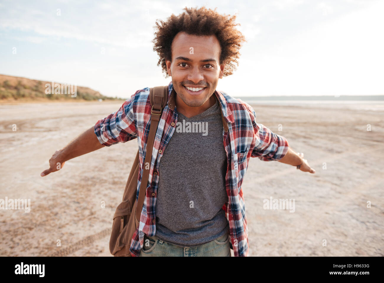 Lächelnd niedliche junge Afrikaner mit Armen verteilt am Strand geöffnet Stockfoto