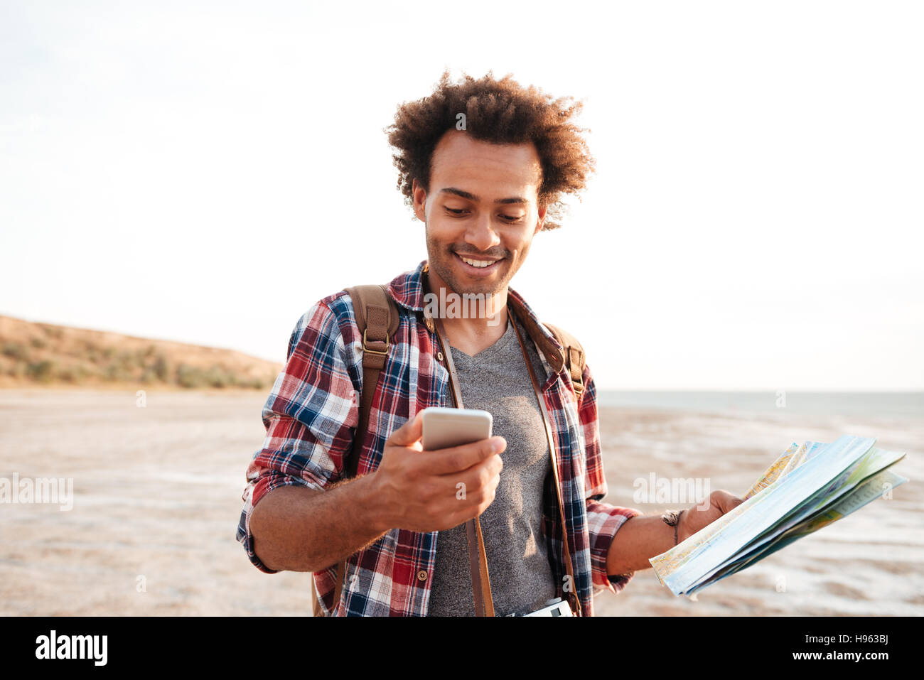 Lächelnd afroamerikanischen jungen Mann mit Karte und Handy im freien Stockfoto