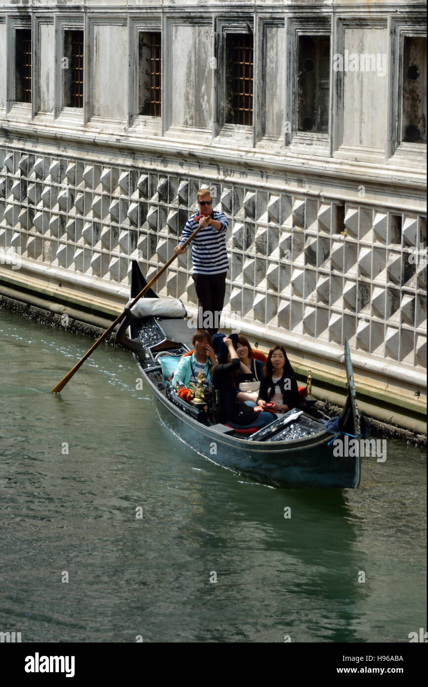 Gondel mit Touristen und Gondoliere auf einem Kanal in Venedig. Stockfoto