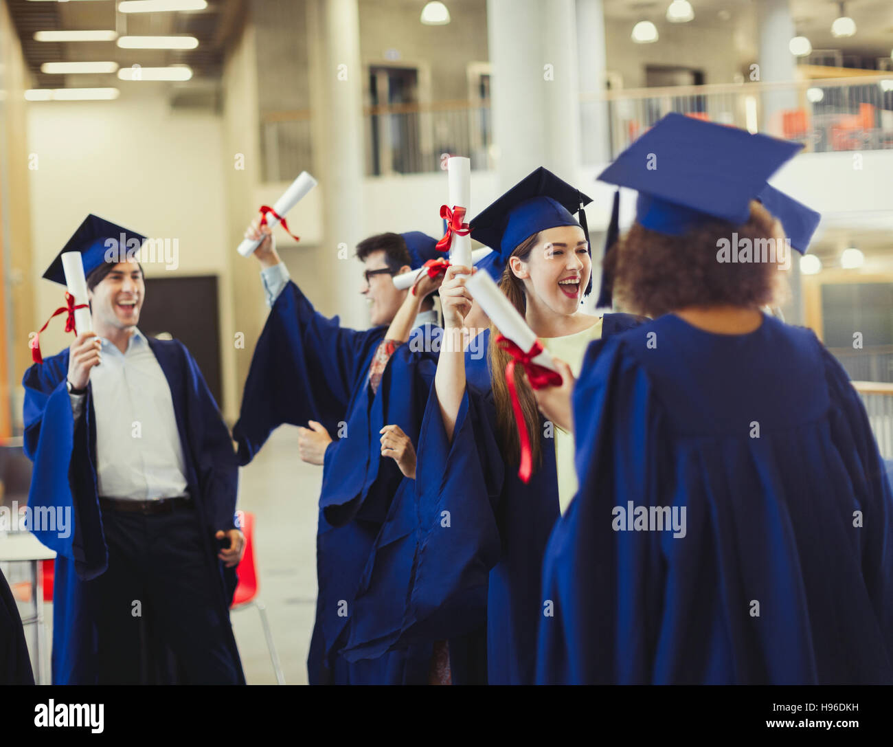 College-Absolventen in Mütze und Mantel hält Diplome Stockfoto