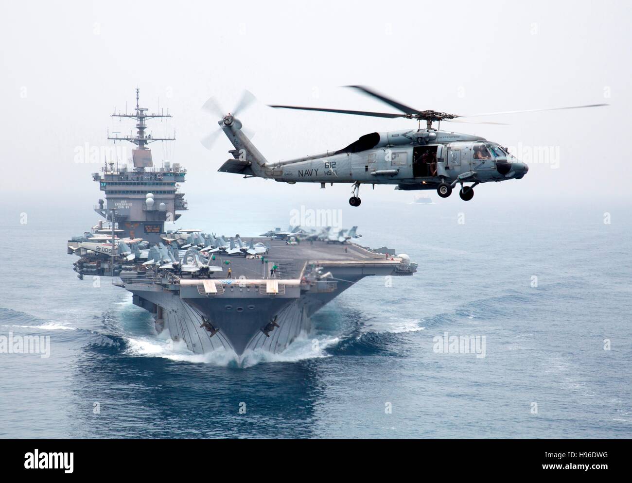 Ein HH - 60H Seahawk Multi-mission Hubschrauber fliegt neben USN Enterprise-Klasse nuklear angetriebene Flugzeugträger USS Enterprise, wie sie die Meerenge Bab El Mandeb-21. Juni 2011 im Roten Meer Transit. Stockfoto