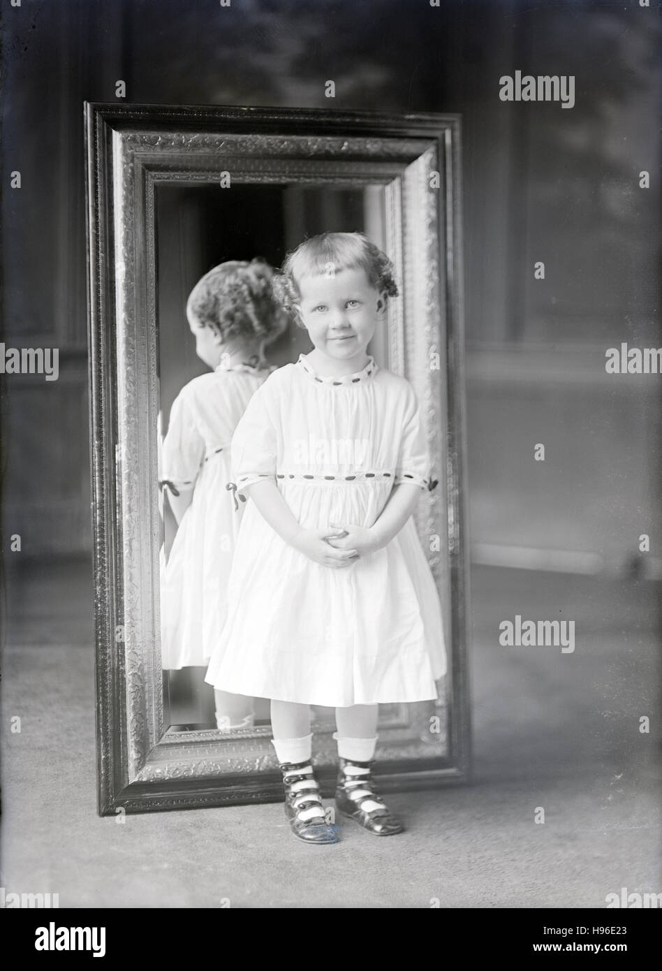 Antike 1900 Foto, Kleinkind Mädchen steht vor einem Spiegel. QUELLE: ORIGINAL FOTONEGATIV. Stockfoto