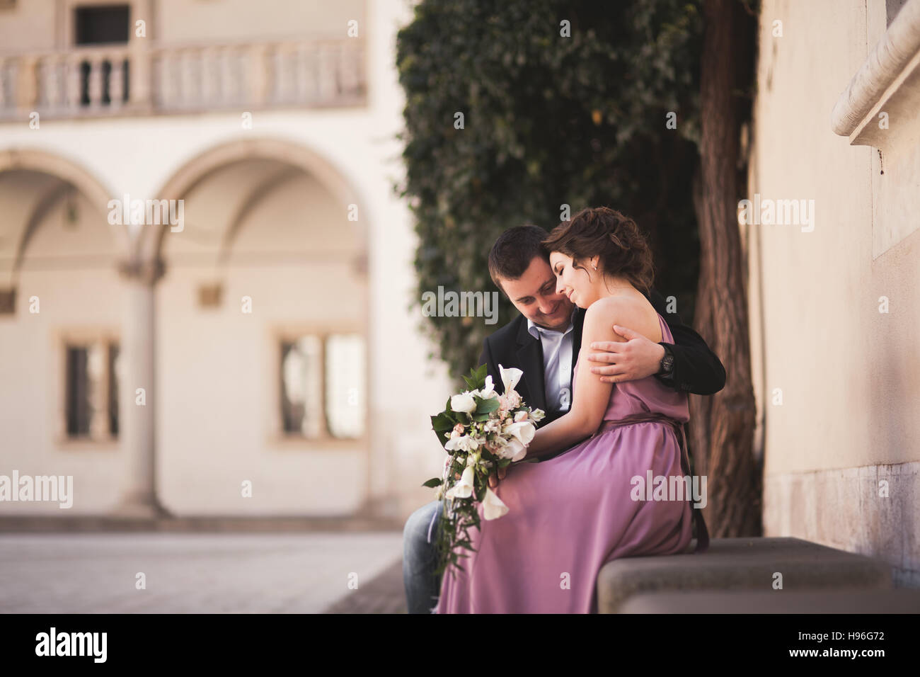 Glückliche Hochzeit paar, Bräutigam, Braut mit rosa Kleid Wände umarmen und lächelnd einander auf dem Hintergrund im Schloss Stockfoto
