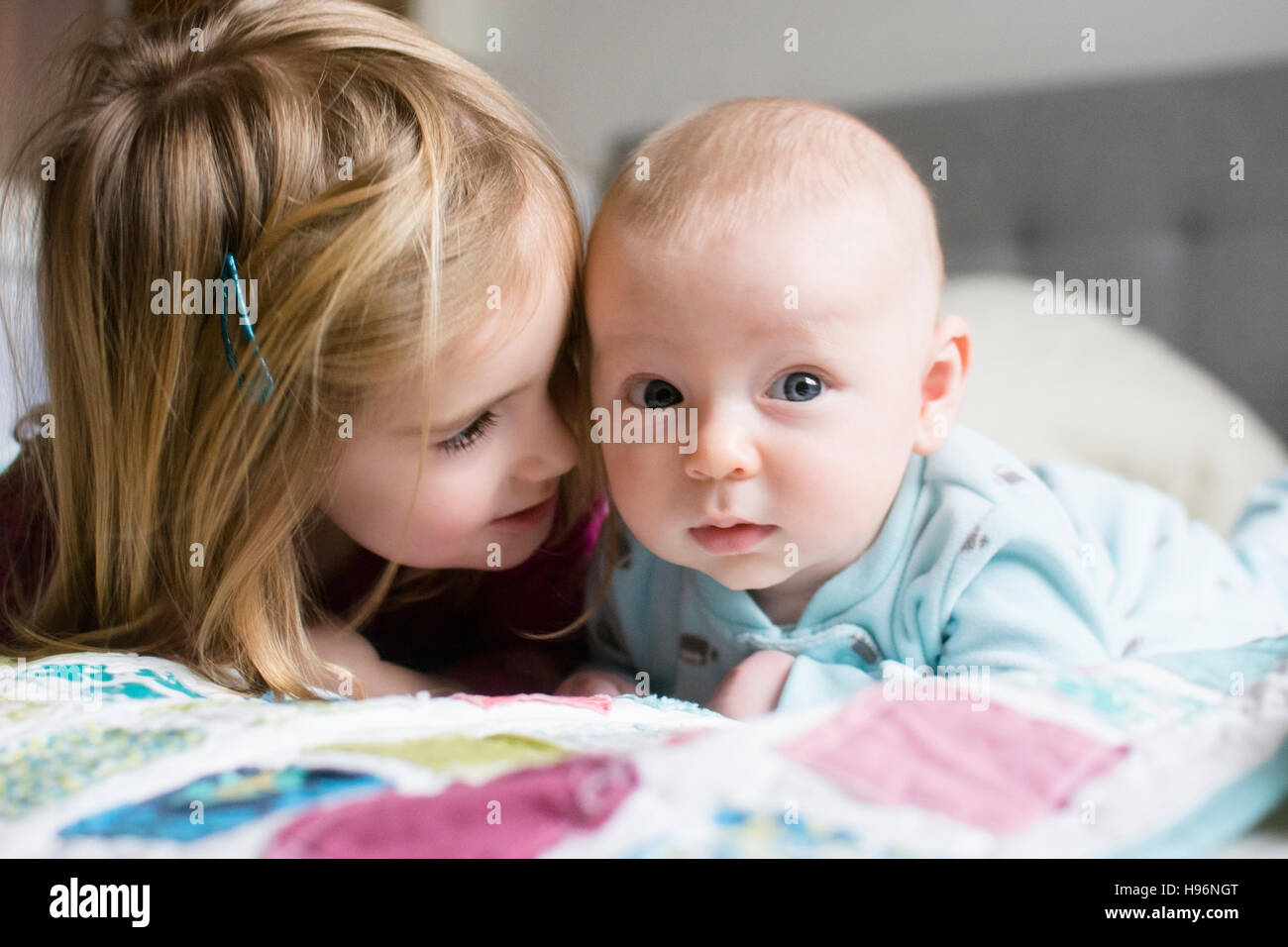 Schwester (2-3) und Bruder (6-11 Monate) auf Bett liegend Stockfoto Schwester (2-3) und Bruder (6-11 Monate) auf Bett liegend Stockfoto
