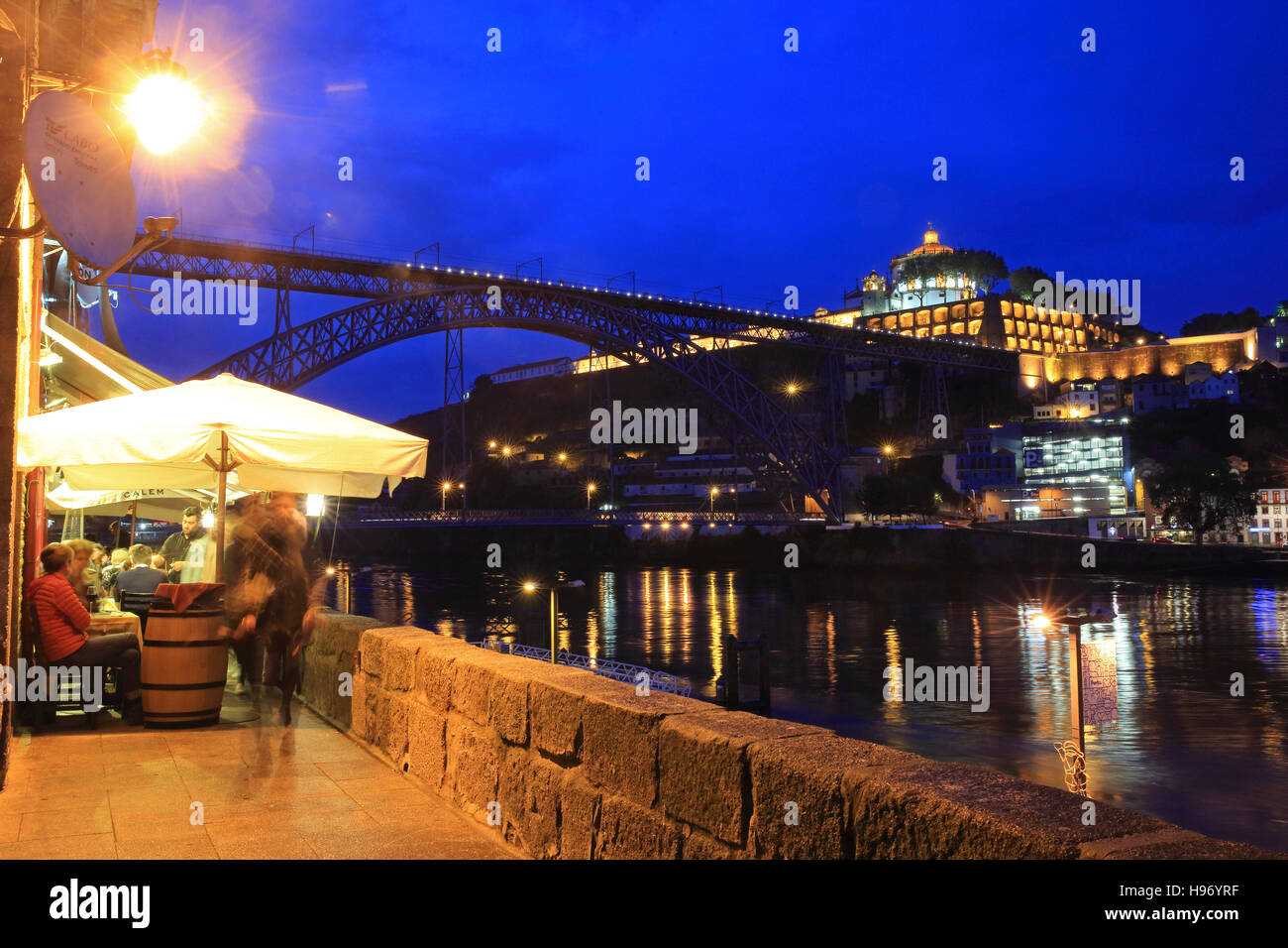 Ein Restaurant am Ufer des Douro, in der Dämmerung mit dem Dom Luis 1 Brücke hinter, in Porto, in Nord-Portugal Stockfoto