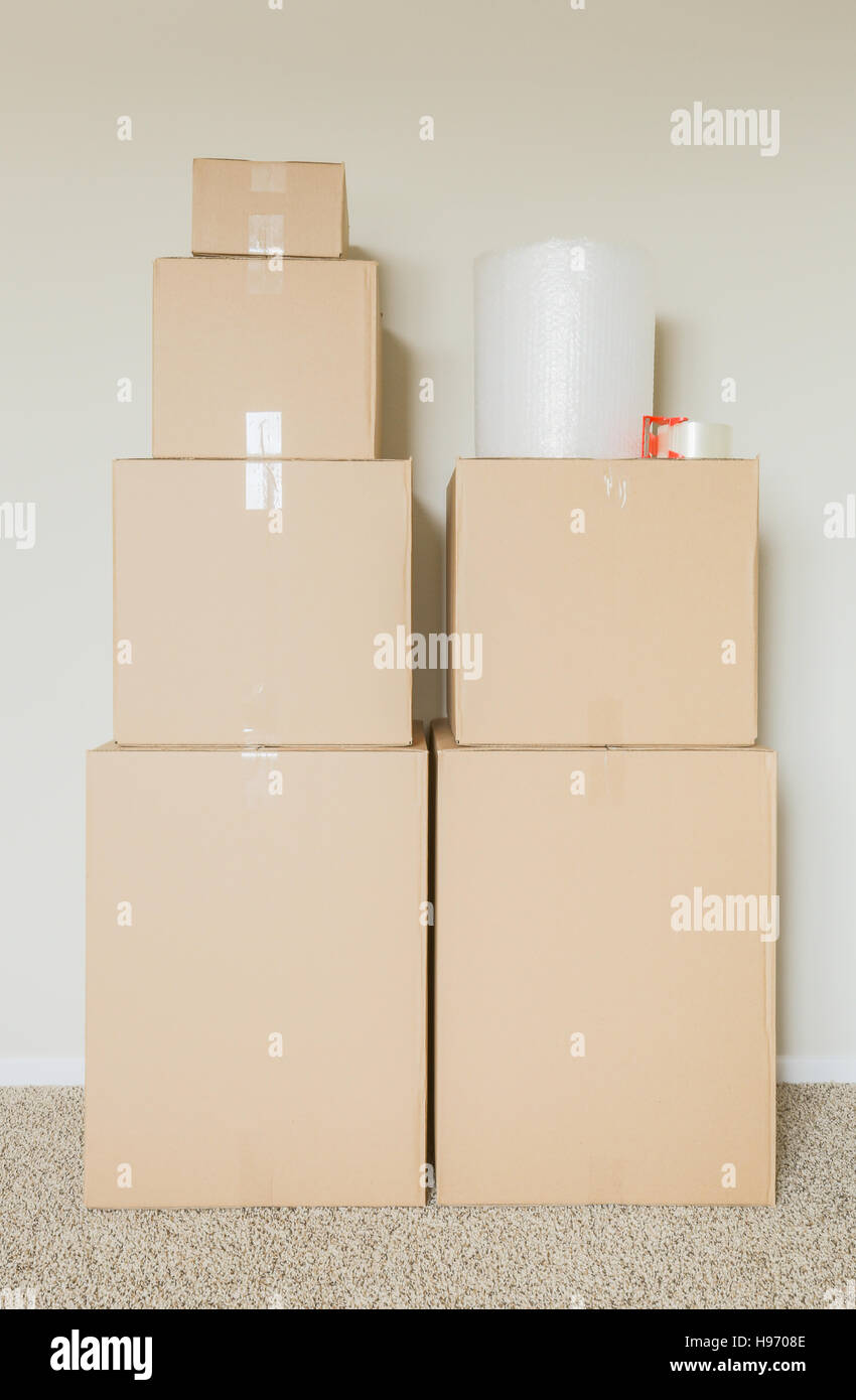 Vielzahl von gepackten Umzugskartons mit Materialien In leeren Raum gegen die Wand. Stockfoto