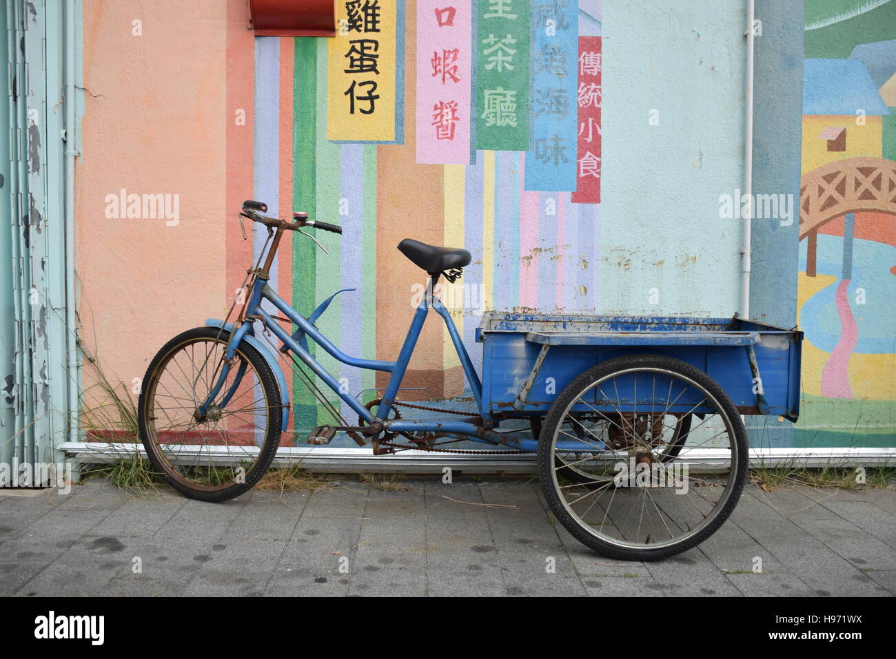 Blau Fahrrad mit Schlitten neben einer farbigen Wand Stockfoto