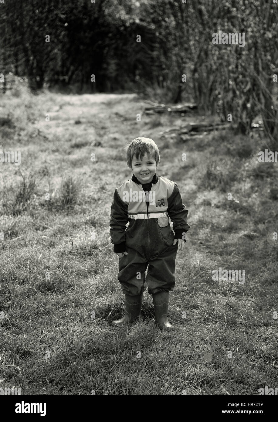 Ein kleiner Junge in der Landschaft waring Overall und Gummistiefel Stockfoto