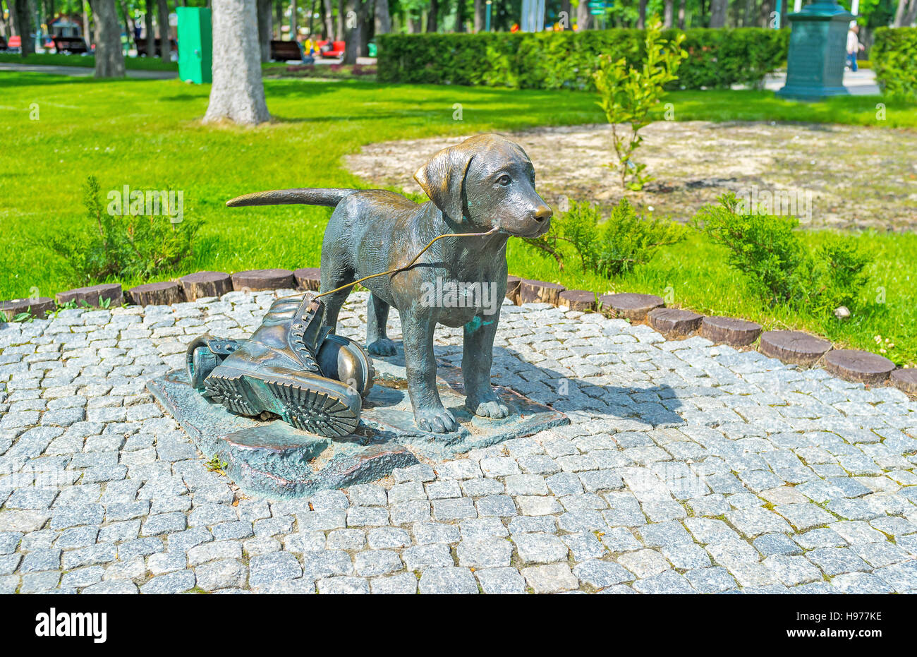 Die Bronzeskulptur eines Welpen, der mit Stiefeln spielt, der Skulpturengarten im Central Park von Charkiv, Ukraine Stockfoto