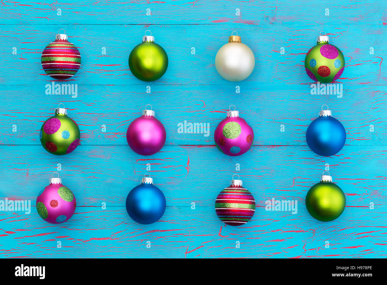 Anordnung der bunten Weihnachtskugeln auf eine exotische blaue Knistern Farbe Holz Hintergrund in ordentlichen Reihen von gemusterten lebendige Christbaumkugeln Stockfoto