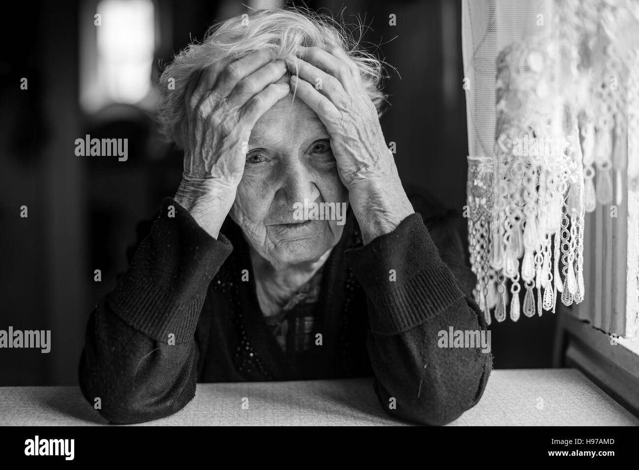 Eine ältere Frau sitzt an einem Tisch in einen depressiven Zustand. Stockfoto