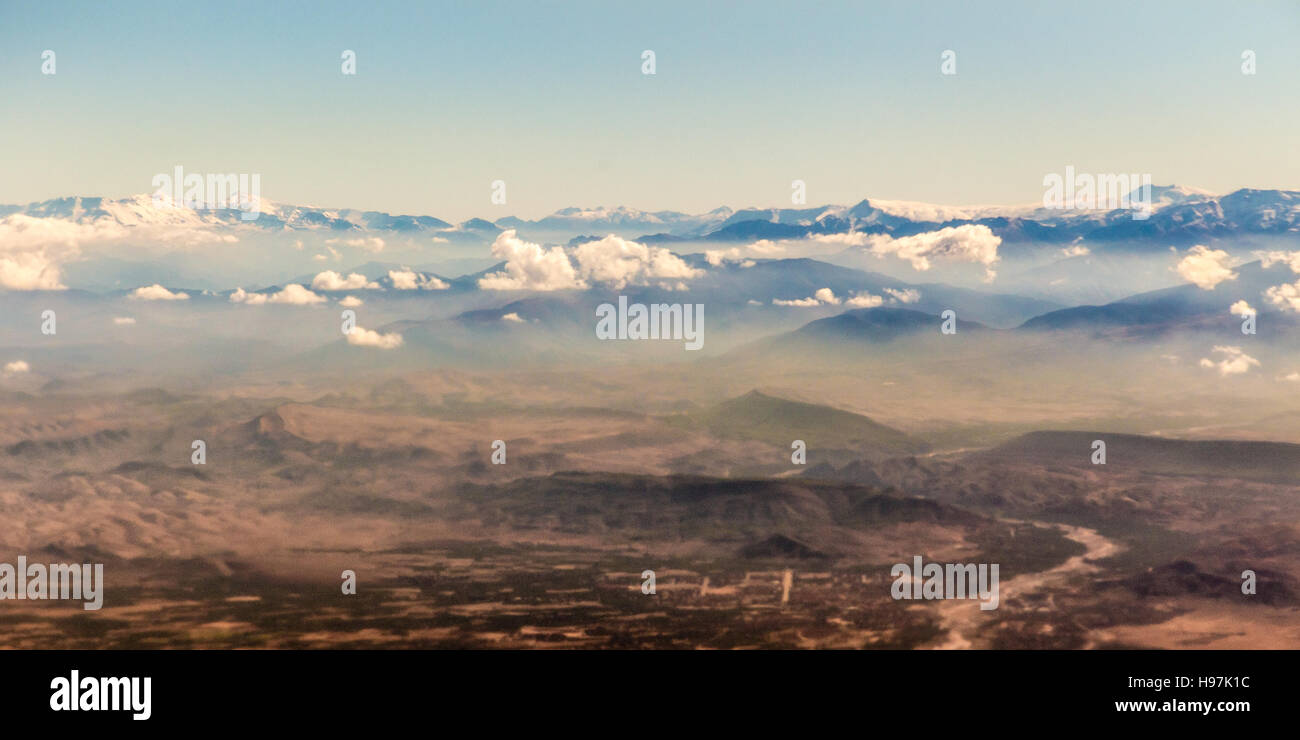 Blick vom Flugzeug auf die Berge und ein Boden unterhalb der Wolke verdoppeln Stockfoto