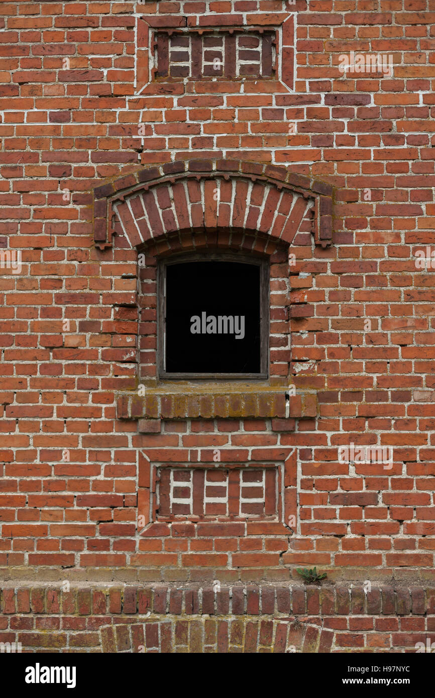 Alte kleine Fenster mit roten Stein in der Mauer eines alten Lagers. Stockfoto Alte kleine Fenster mit roten Stein in der Mauer eines alten Lagers. Stockfoto