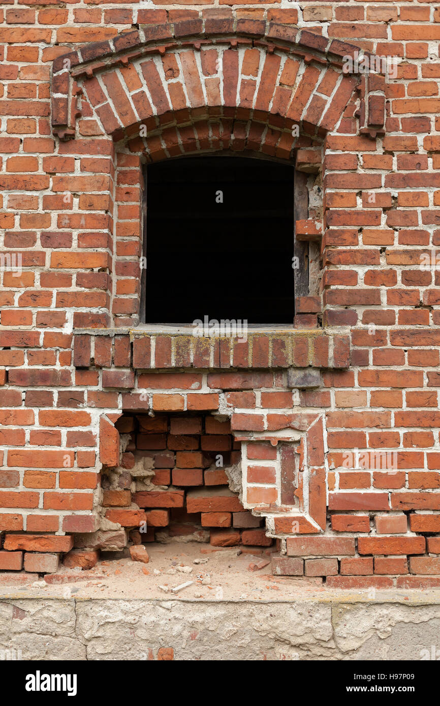 Alte kleine Fenster mit roten Stein in der Mauer eines alten Lagers. Stockfoto