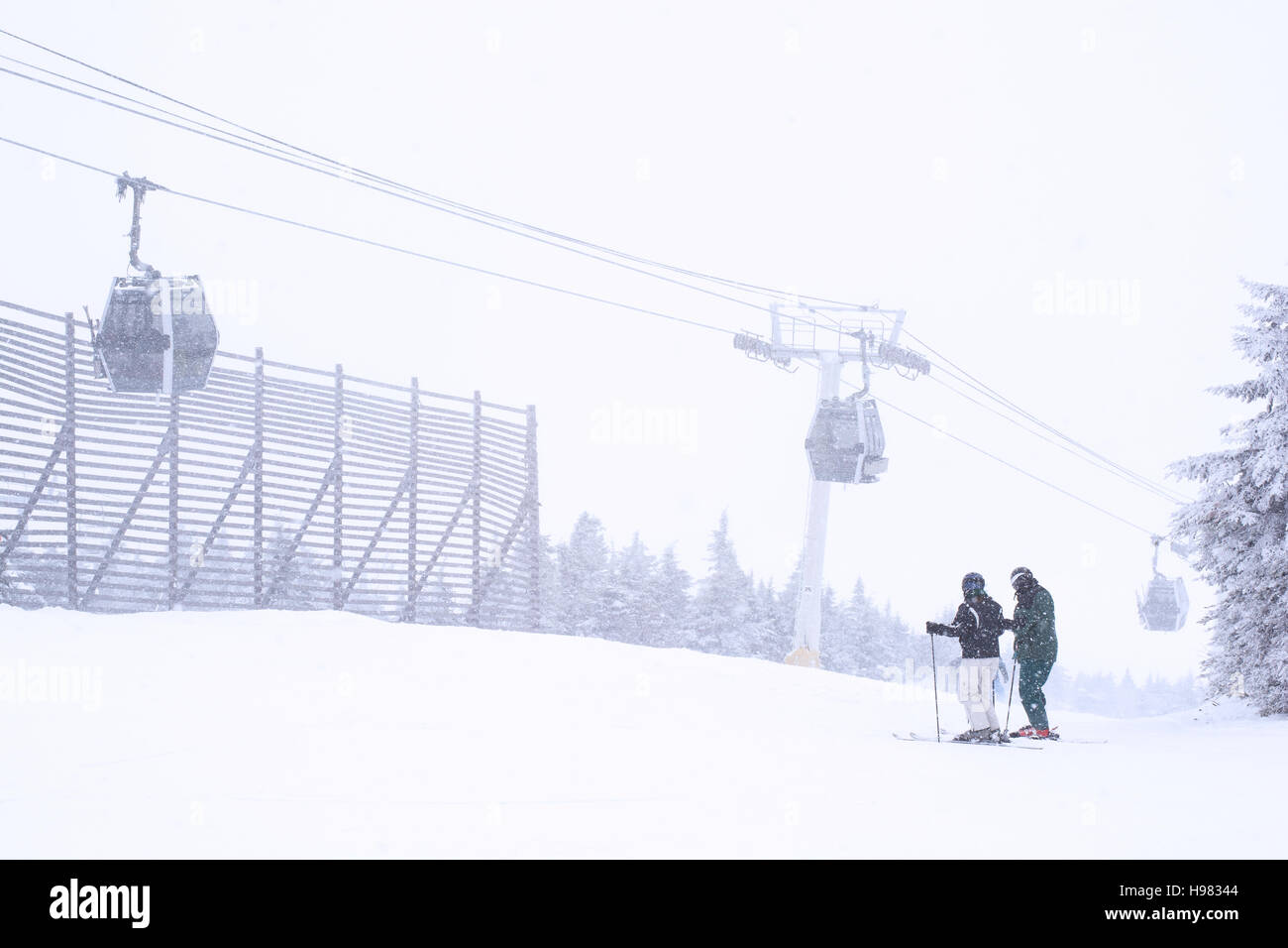 Skifahrer steht in der Nähe von der Spitze eines Berges mit einer Gondel schwach sichtbar durch den Schnee ski Stockfoto