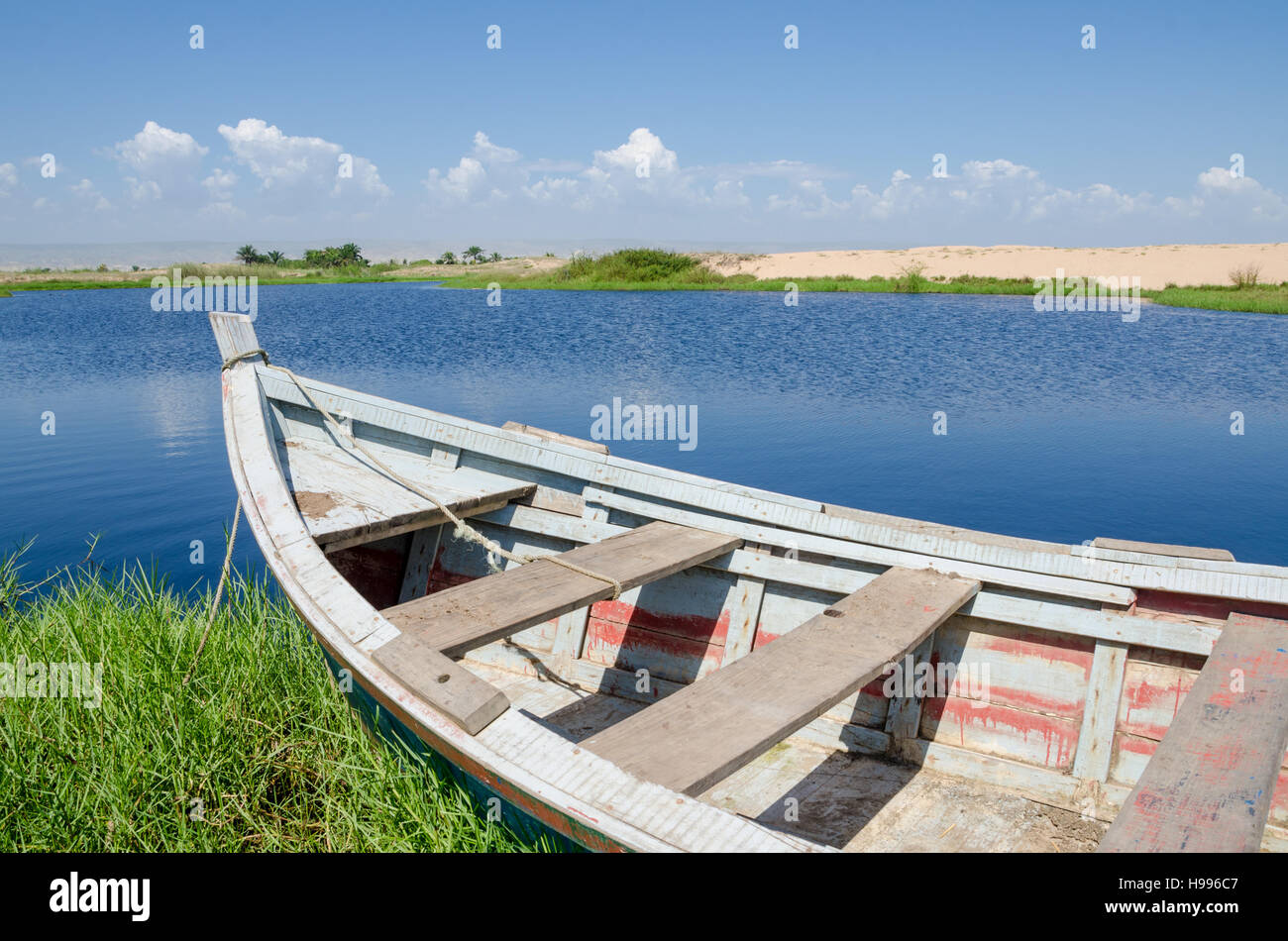 Angelboot/Fischerboot verankert in Lagune mit grünem Rasen und Dünen und Wolken im Hintergrund in der Nähe von Lobito, Angola Stockfoto