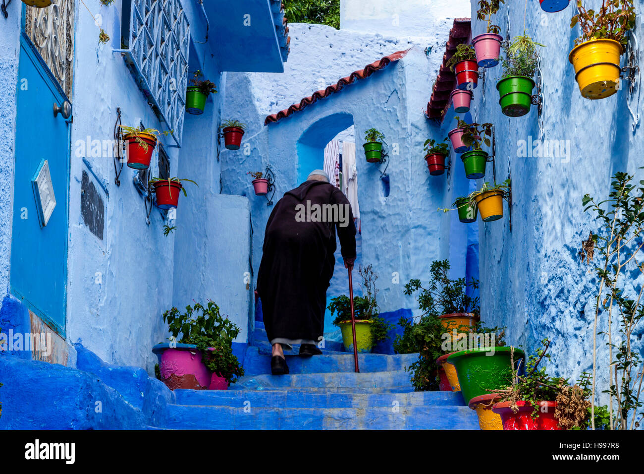 Ein älterer Mann zu Fuß hinauf eine bunte Straße In der Medina, Chefchaouen, Marokko Stockfoto