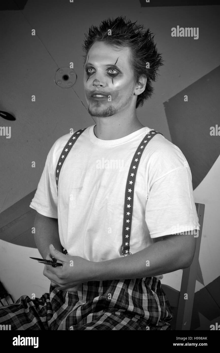 Schwarz / weiß Darstellung von scary Clown im Zirkus Einstellung sitzen und halten der Schere Stockfoto
