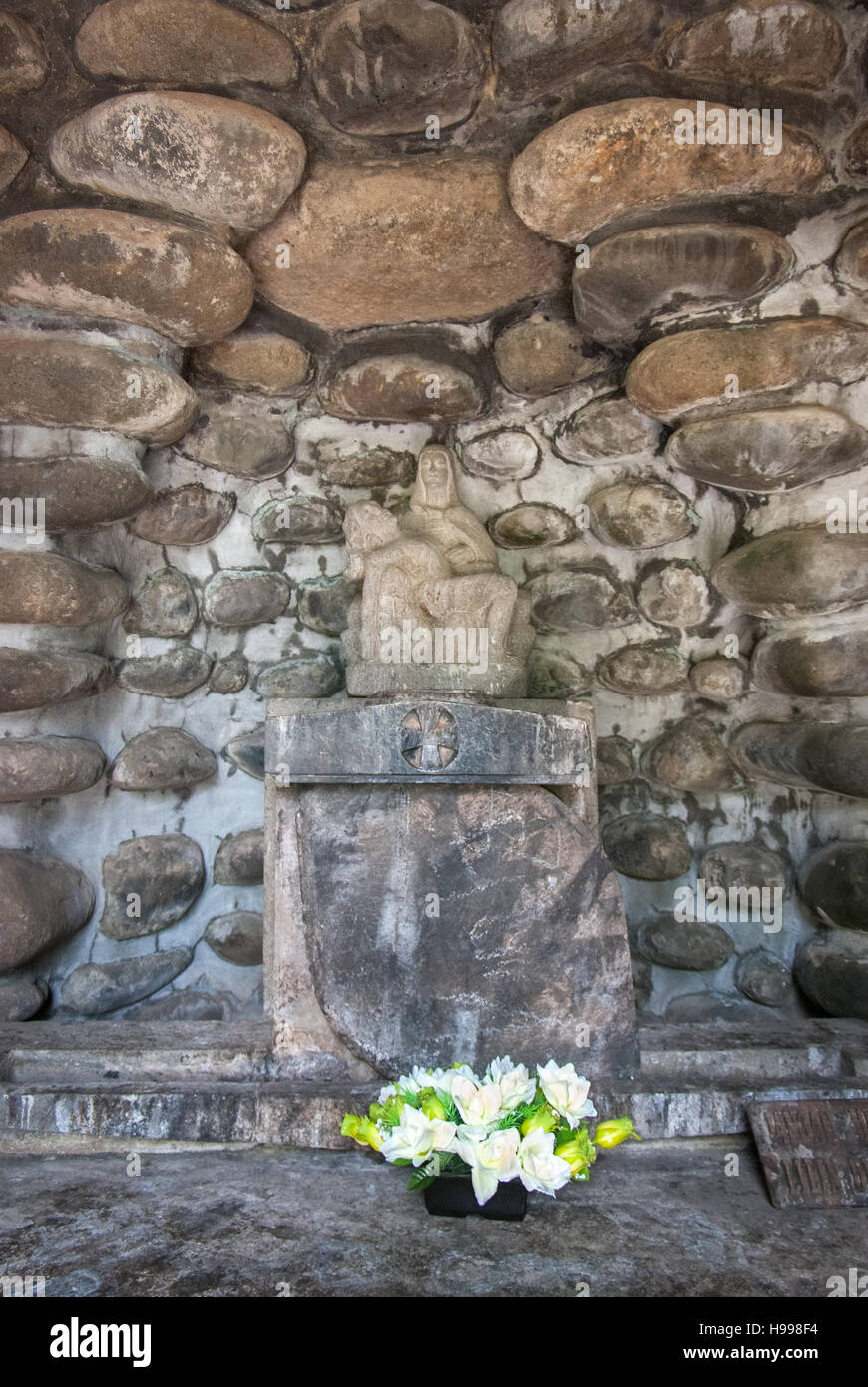 Pietà-Statue auf einem Steinaltar mit Blumen in der Kirche Puh Sarang, einem bekannten Gotteshaus und religiösem Reiseziel in Kediri, Indonesien. Stockfoto