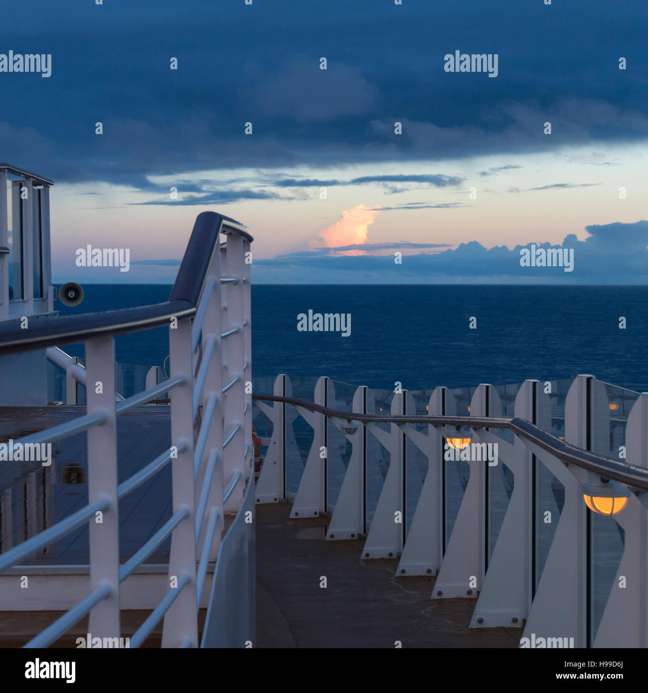 Am frühen Morgen auf dem oberen Deck eines Kreuzfahrtschiffes zur blauen Stunde vor Sonnenaufgang mit einem nassen Deck und stürmischen Himmel Stockfoto