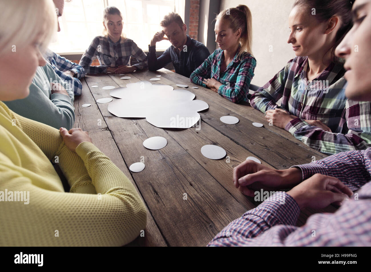 Hipster Geschäft Teamarbeit brainstorming-Sitzung Planungskonzept, Leute sitzen um den Tisch herum mit weißem Papier geformt wie Dialog Wolke Stockfoto