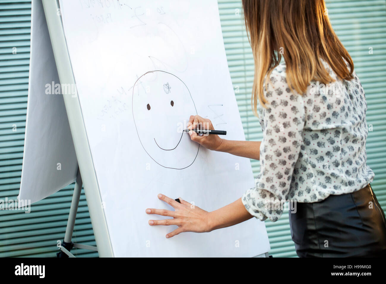 Geschäftsfrau, die Zeichnung menschlichen Gesichts auf flipchart Stockfoto